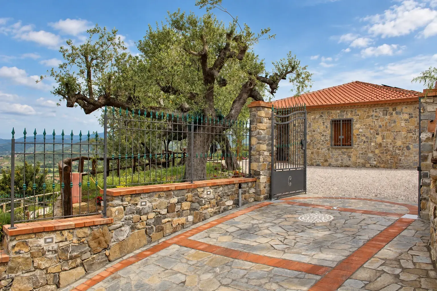 Ingresso dell'agriturismo Il Vecchio Carrubo ad Ascea, con edificio in pietra, cancello e grande ulivo